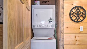 Ein kleiner Waschraum mit Waschmaschine und Trockner, Holzvertäfelung und einer dekorativen Scheibe an der Wand.