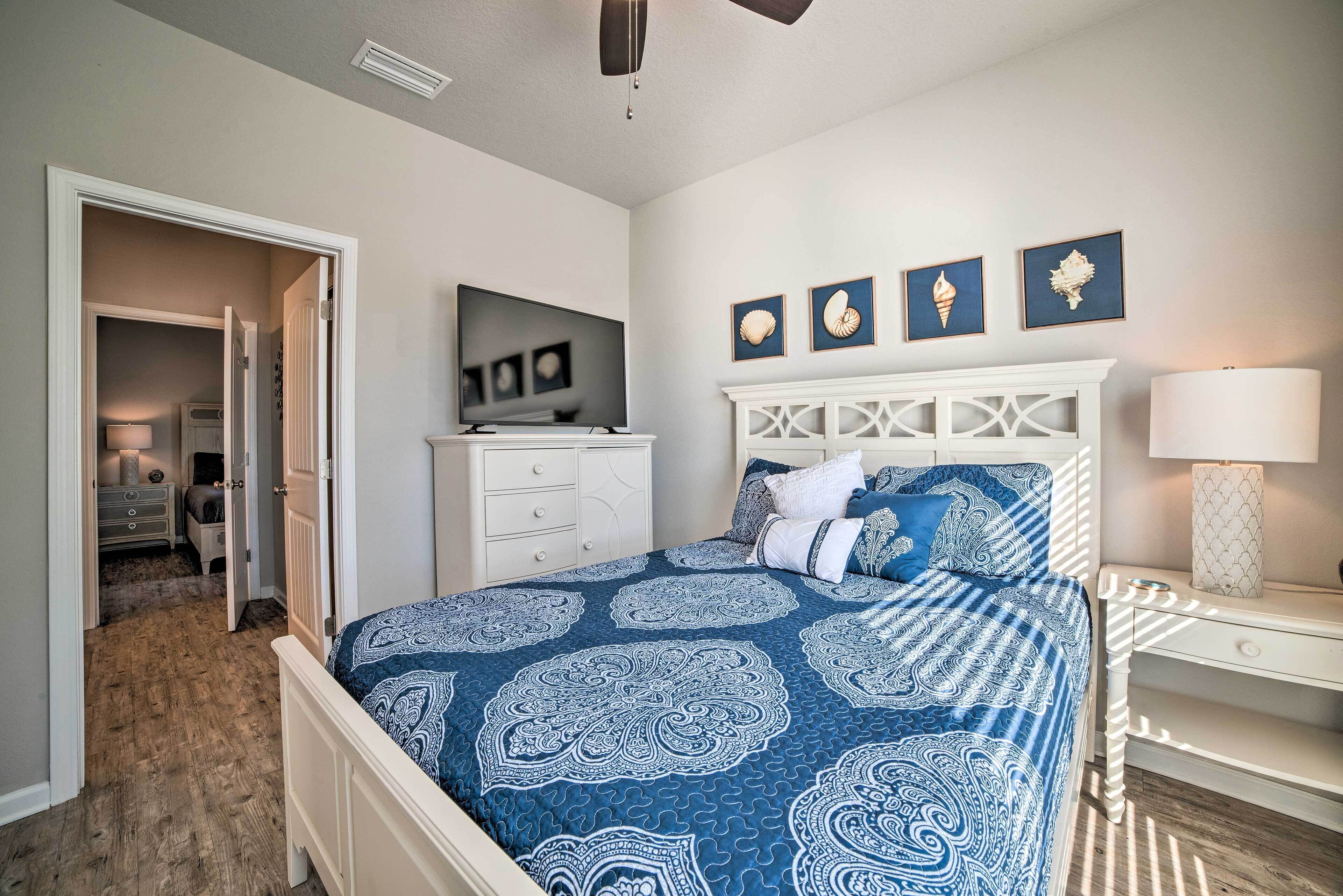 A bedroom with a bed, a dresser, a television, and a door leading to another room.
