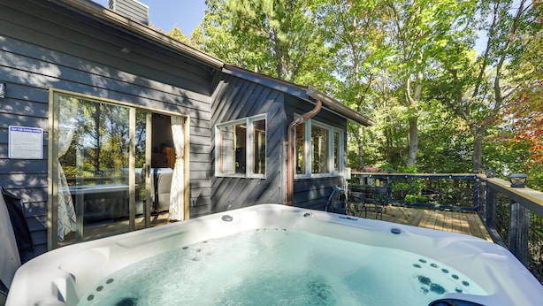 Un jacuzzi en una terraza de madera, con una casa al fondo.