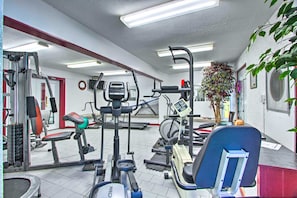 Ein Fitnessraum mit unterschiedlichen Trainingsgeräten, einem Laufband und einem an der Wand befestigten Fernseher.