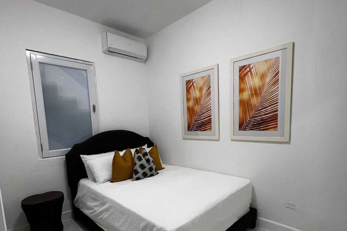 A bedroom with a bed, a window, and two framed pictures on the wall.