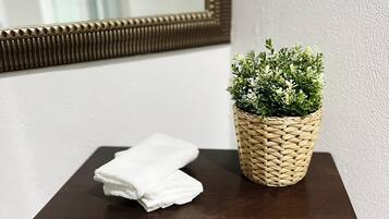 A small wooden table with a woven basket containing green plants and a folded white towel.