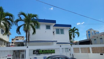 Un edificio de dos pisos con fachada blanca y techo azul.
