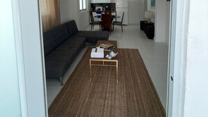 A modern living room with a sectional sofa, a coffee table, and a dining area with a table and chairs. - Janer House (San Juan)