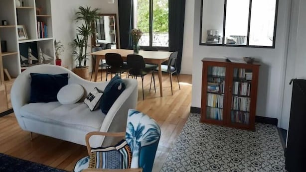 Un salon moderne comprenant un canapé, une table à manger, des chaises, une bibliothèque et une grande fenêtre.