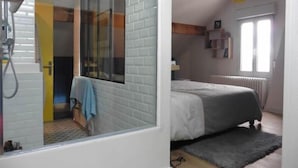 Une chambre à coucher avec un lit, une fenêtre, un radiateur et un luminaire suspendu.