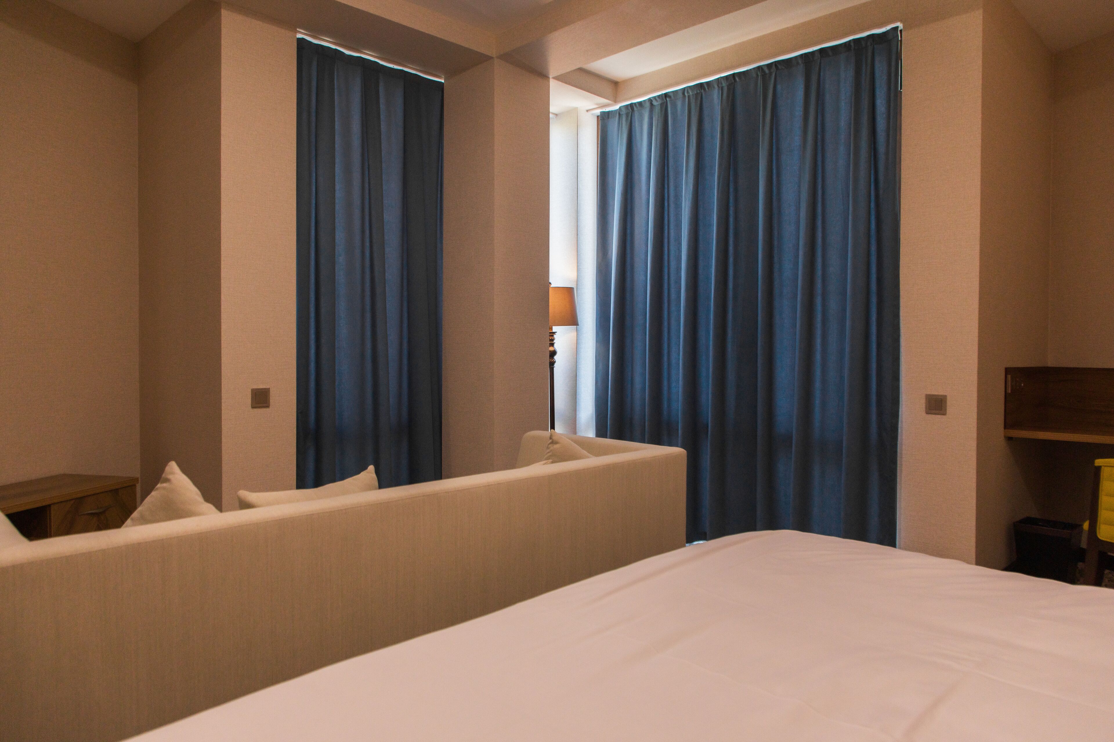 A hotel room with a bed, a sofa, and curtains.