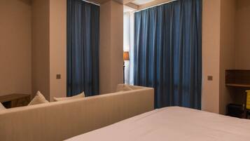 A hotel room with a bed, a sofa, and curtains.