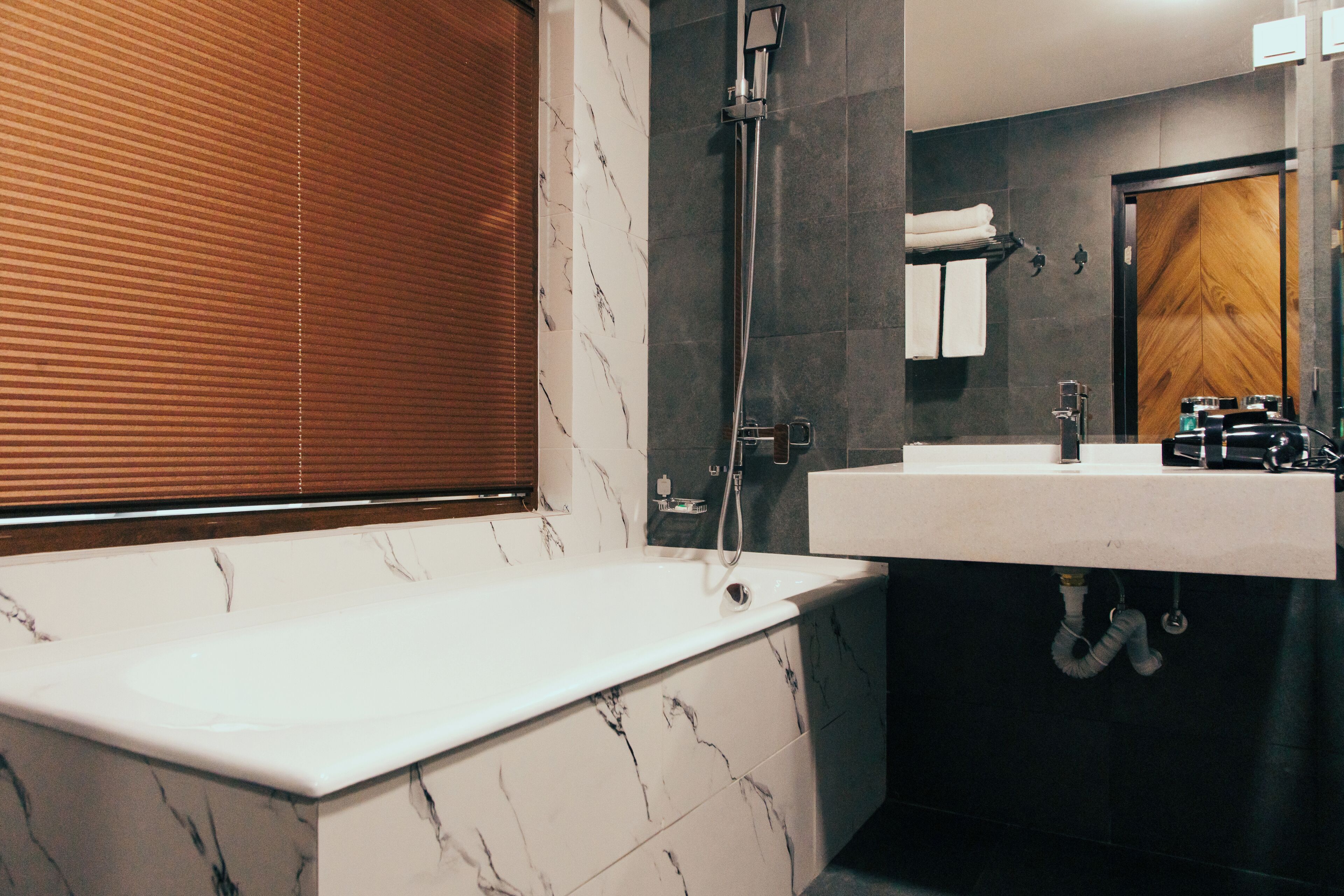 Un baño moderno con una bañera de mármol, un lavabo y una ducha.