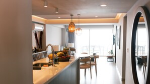 Een moderne keuken met een centraal eiland, een eethoek met een ronde tafel, en een grote spiegel aan de muur.