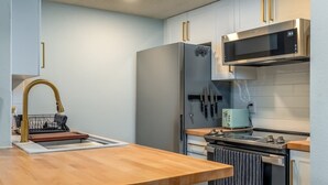 Une cuisine moderne dotée d’un plan de travail en bois, d’appareils électroménagers en acier inoxydable et d’un égouttoir à vaisselle.