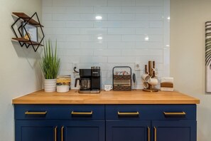 Et køkken med kaffemaskine, en kurv med brød og en plante.