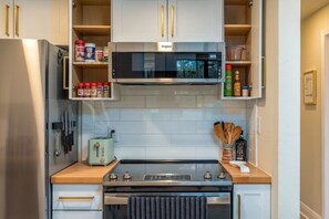 A compact kitchen with a microwave, toaster, and stainless steel appliances. - Sleep 4 | King Bed | Golf Course (Daphne)