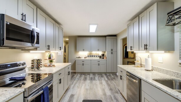 Una cocina moderna con electrodomésticos de acero inoxidable, suelo de madera clara y una isla central con fregadero.