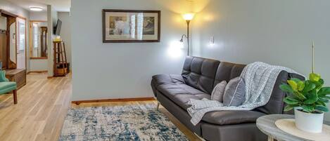 A modern living room with a leather sofa, a round coffee table, and a large potted plant.