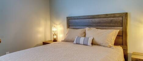 A neatly made bed with a wooden headboard, a bedside lamp, and a pillow.