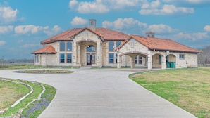 A large, two-story house with a red-tiled roof, multiple windows, and a central entrance.