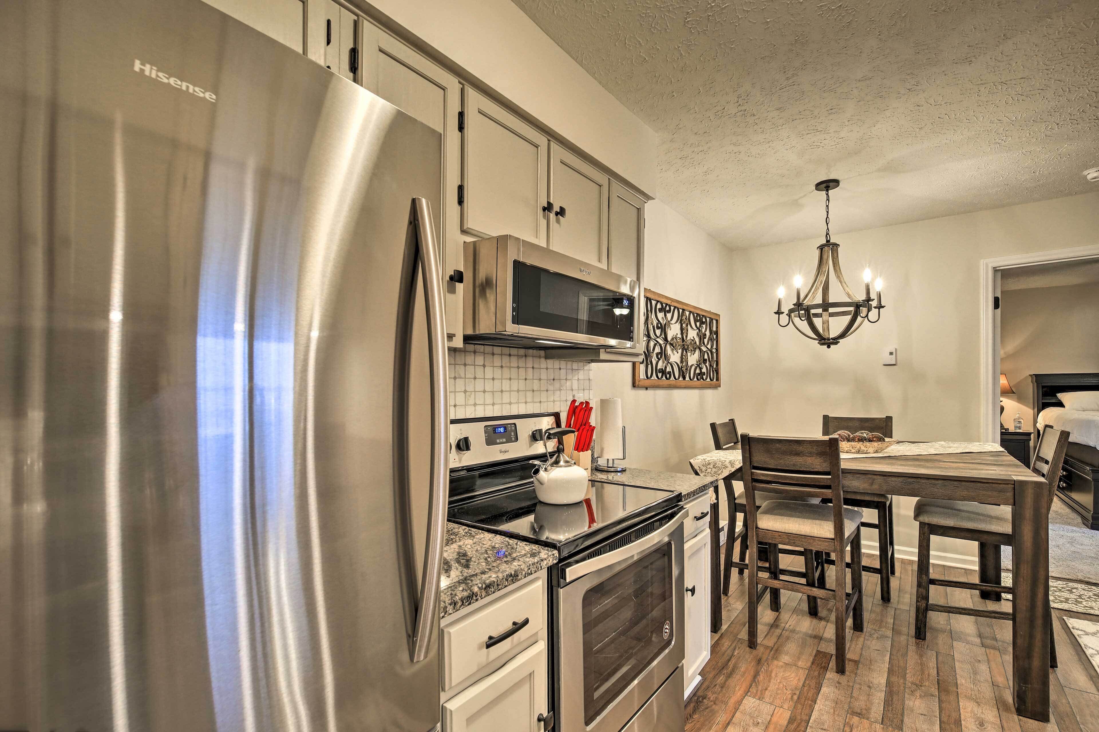 A modern kitchen with stainless steel appliances, a microwave, and a chandelier.