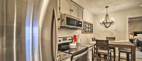 A modern kitchen with stainless steel appliances, a microwave, and a chandelier.