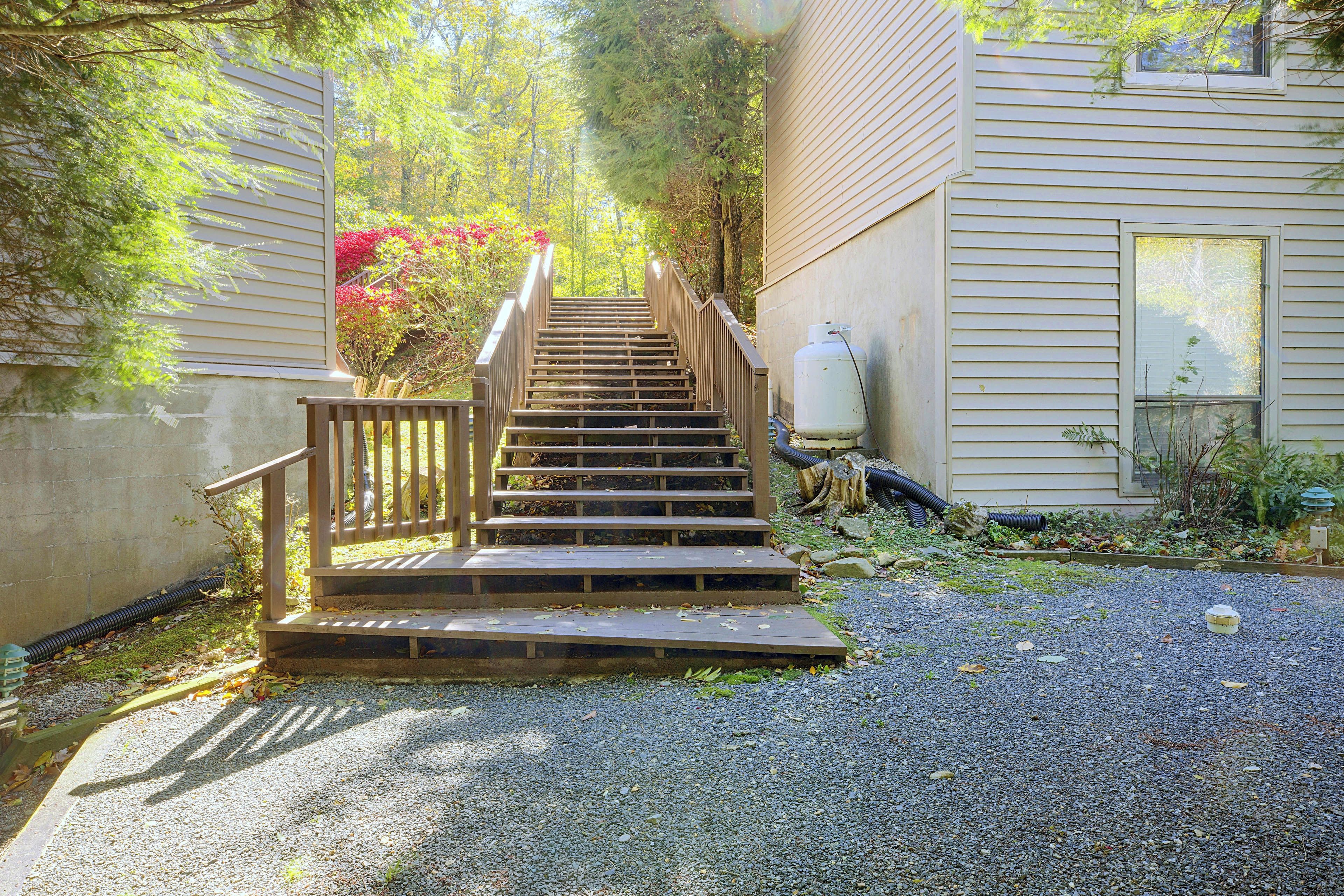 A wooden staircase leading up to a house with a gravel driveway.