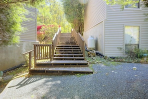 A wooden staircase leading up to a house with a gravel driveway.