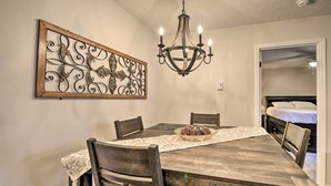 A dining area with a wooden table, chairs, a chandelier, and a decorative metal piece on the wall. - Deck & Grill: Modern Sugar Mtn Escape! (Banner Elk)