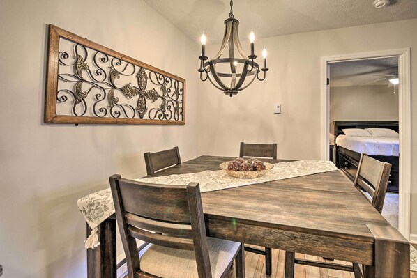 A dining area with a wooden table, chairs, a chandelier, and a decorative metal piece on the wall. - Deck & Grill: Modern Sugar Mtn Escape! (Banner Elk)