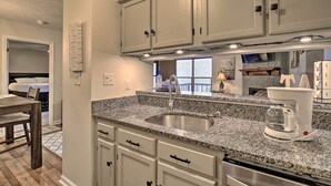 A kitchen with granite countertops, a stainless steel sink, white cabinets, and a built-in dishwasher. - Deck & Grill: Modern Sugar Mtn Escape! (Banner Elk)