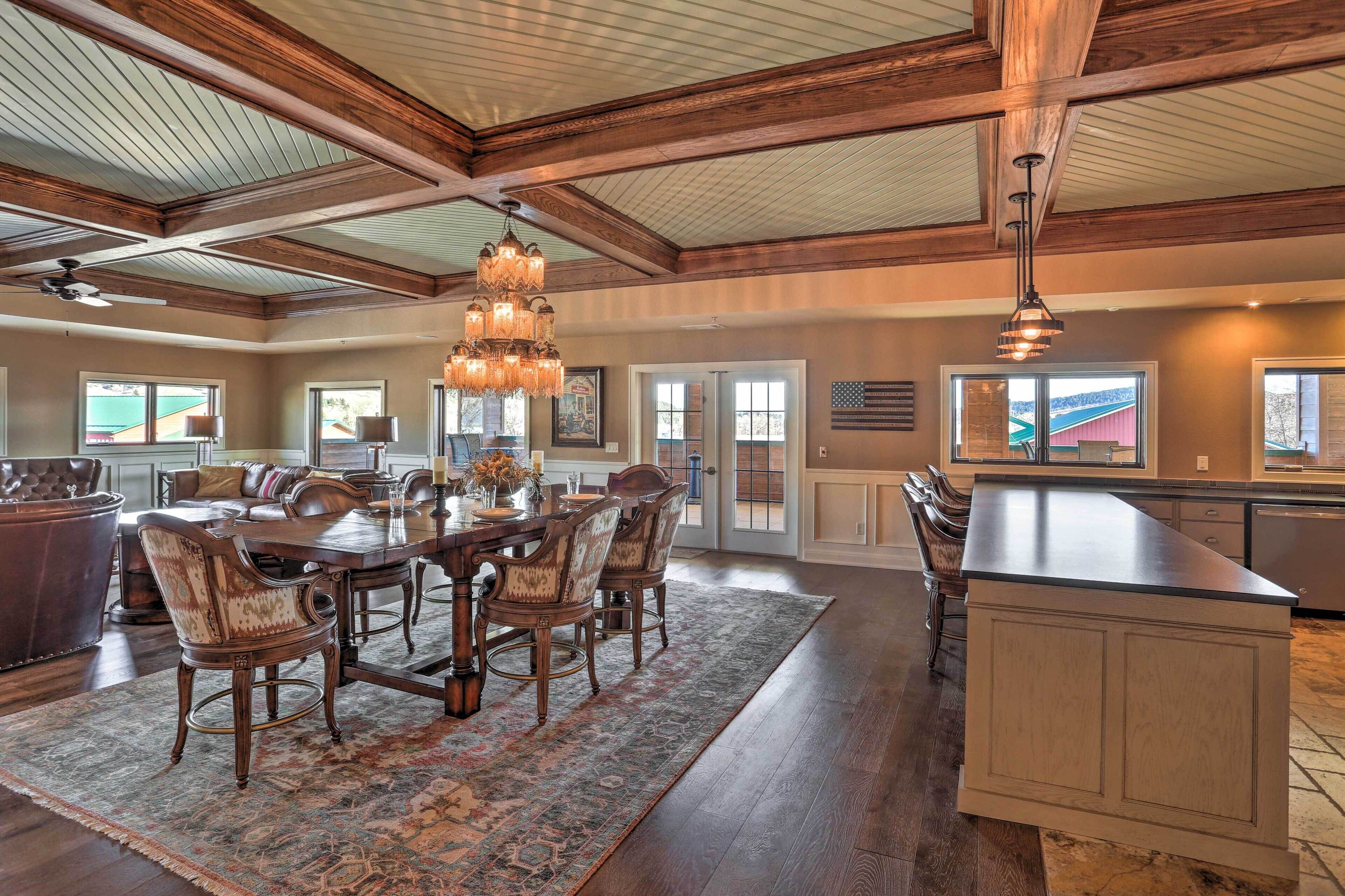 A spacious kitchen with a large island, wooden ceiling beams, and a chandelier.