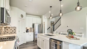 A modern kitchen with white cabinets, stainless steel appliances, a central island, and pendant lighting. - Spacious House: Pool Access Nearby & 4 Mi to Beach (Millville)