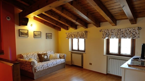 A cozy room with a wooden ceiling, a sofa, a radiator, and a window with curtains. - Sleeping in the Prosecco Hills. House suitable for families or groups of friends. (Combai)