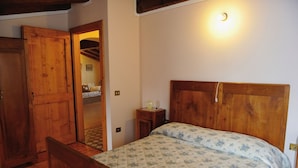 A bedroom with a wooden bed, a nightstand, a wooden wardrobe, and a door leading to another room. - Sleeping in the Prosecco Hills. House suitable for families or groups of friends. (Combai)