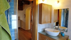 A bathroom with a glass shower enclosure, wooden cabinets, a large sink, and a mirror. - Sleeping in the Prosecco Hills. House suitable for families or groups of friends. (Combai)