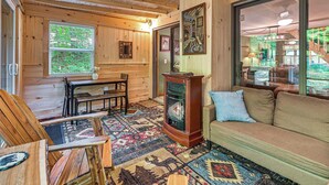 A cozy cabin interior with a wooden interior, a fireplace, a sofa, and a dining area.