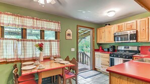A kitchen with wooden cabinets, a red countertop, and a dining area with a table set for four.