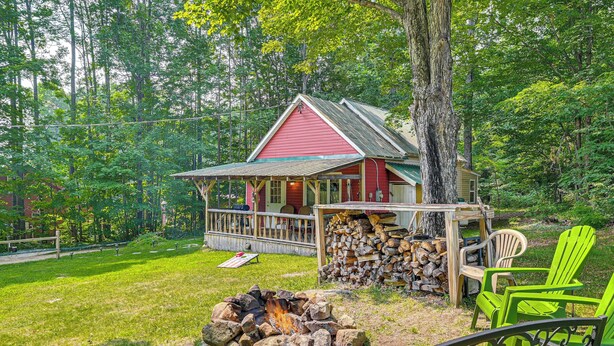 A cabin with a porch, a fire pit, and outdoor seating.