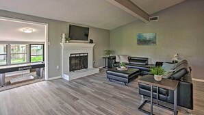 Ein Wohnzimmer mit Kamin, Ledersofas, einem Couchtisch und einem Fernseher, der über dem Kamin montiert ist.