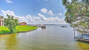 Una propiedad frente al lago con un muelle, una construcción pequeña y una zona con césped.