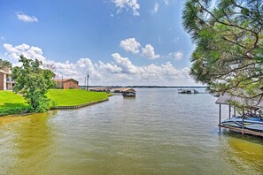 A lakeside property with a dock, a small building, and a grassy area. - Cedar Creek Reservoir Home w/ Deck & Dock (Mabank)