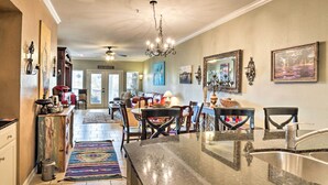 A spacious kitchen with a granite countertop, a stainless steel sink, and a dining area with a red sofa and wooden chairs. - Lakefront Lago Vista Condo w/ Resort Amenities! (Leander)