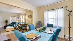 Uma área de refeições com uma mesa comprida para quatro pessoas, cadeiras estofadas azuis e uma mesa de buffet com um arranjo de plantas.