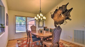 A dining room with a wooden table, chairs, and a chandelier. There is a large animal hide on the wall and a window with blinds. - 'high Gravity' Banner Elk Custom Chalet w/ Views! (Banner Elk)