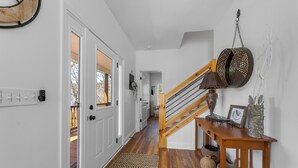 A hallway with wooden flooring, white walls, a wooden staircase, and a hanging lantern. - Charming Murphy House With Deck & River Views! (Murphy)