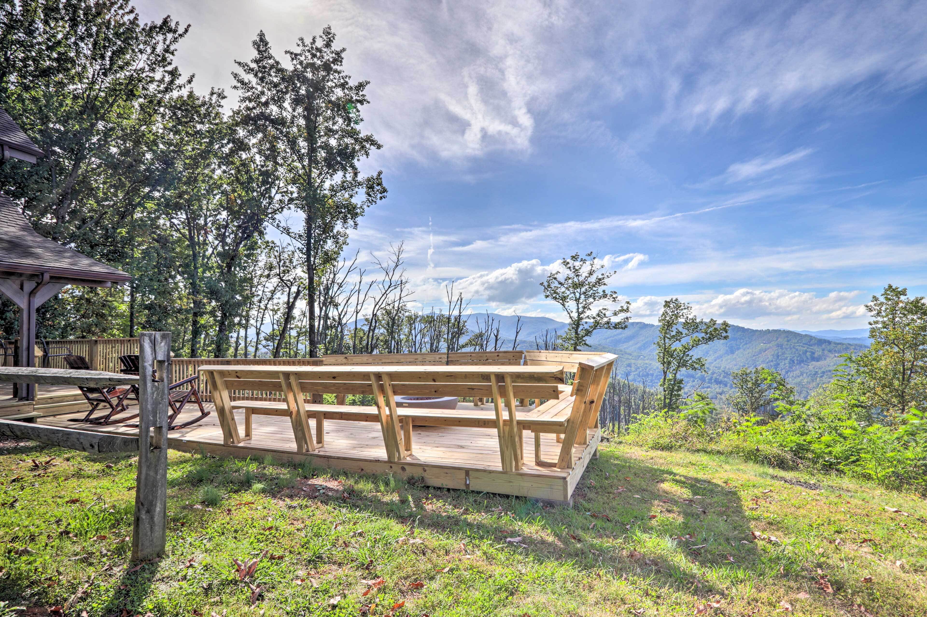 A wooden deck with benches overlooking a mountainous landscape.