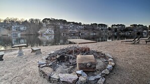 A lakeside view with a fire pit, benches, and a dock. - Lakefront Retreat w/ Dock & Beach: 2 Miles to Golf (Bella Vista)