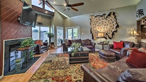 A spacious living room with a fireplace, leather sofas, a coffee table, and a large rug. - Lakefront Retreat w/ Dock & Beach: 2 Miles to Golf (Bella Vista)