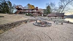 A large, multi-story building with a stone retaining wall and a circular fire pit area. - Lakefront Retreat w/ Dock & Beach: 2 Miles to Golf (Bella Vista)