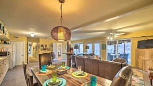 A dining area with a wooden table set for four, surrounded by leather chairs. A hanging light fixture is above the table. - Lakefront Retreat w/ Dock & Beach: 2 Miles to Golf (Bella Vista)