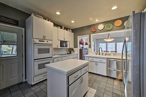 A modern kitchen with white cabinetry, stainless steel appliances, and a central island.