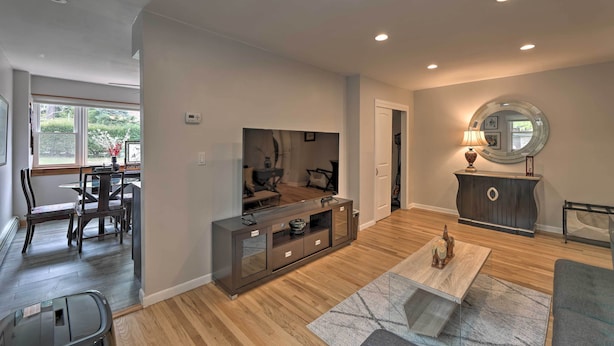 A modern living room with a dining area, wooden flooring, a sofa, a coffee table, and a sideboard. - Yonkers Apt w/ Balcony: Walk to Train Station! (Yonkers)